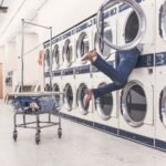 A funny scene in a laundromat with a person partially inside a dryer, highlighting everyday mishaps.