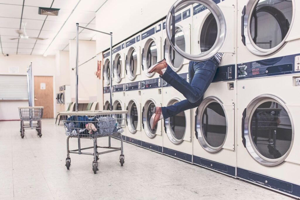 A funny scene in a laundromat with a person partially inside a dryer, highlighting everyday mishaps.