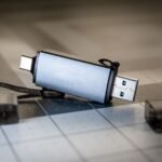 High-quality close-up of a dual USB-C and USB-A flash drive on a sleek grid-patterned background.