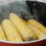 Close-up of steaming corn cobs in a pot, ideal for food imagery.