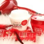 High-quality shot of L'Oreal hair products and hair dryer on white fur background.