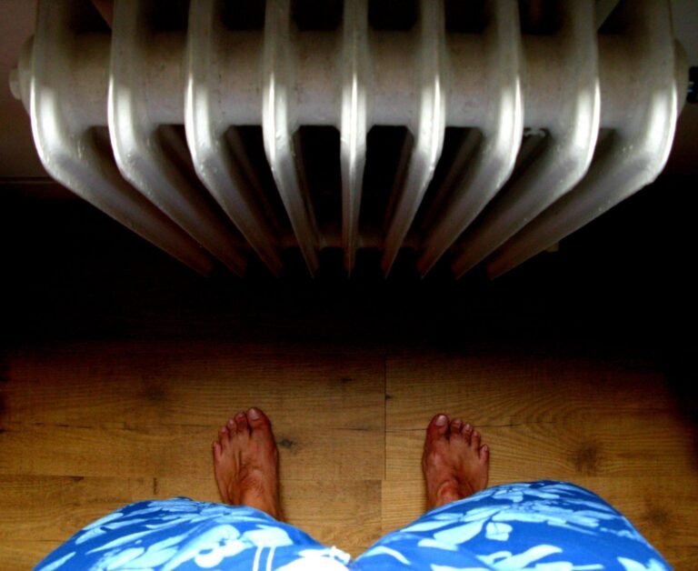 A unique perspective from above showing bare feet standing on wooden floor near a radiator.