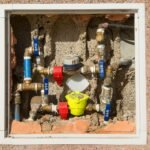 Detailed view of a complex water meter setup embedded in a concrete wall.