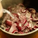 Close-up of red onions being soaked with water in a cooking pot.