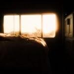Tranquil bedroom interior bathed in warm sunrise light through the window, creating a serene atmosphere.