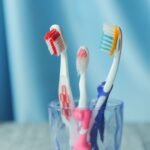 A trio of vibrant toothbrushes in a glass on a blue background, emphasizing dental hygiene.