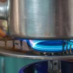 A detailed image showing a gas stove burner with a pot above, highlighting kitchen heat and flame.