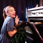Smiling woman in 1950s kitchen baking a delicious homemade pie.