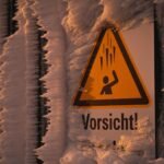 Frozen caution sign covered in ice and frost on a winter day.