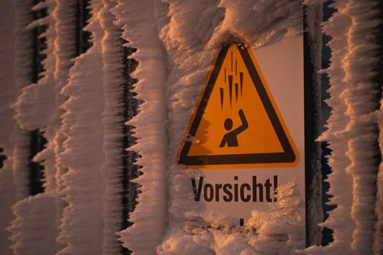 Frozen caution sign covered in ice and frost on a winter day.
