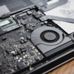Detailed view of a laptop's internal circuitry and cooling fan showcasing technology and engineering.