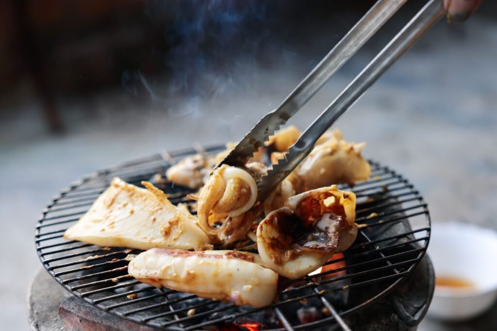 Fresh seafood being grilled on a charcoal barbecue in Rạch Giá, Vietnam.