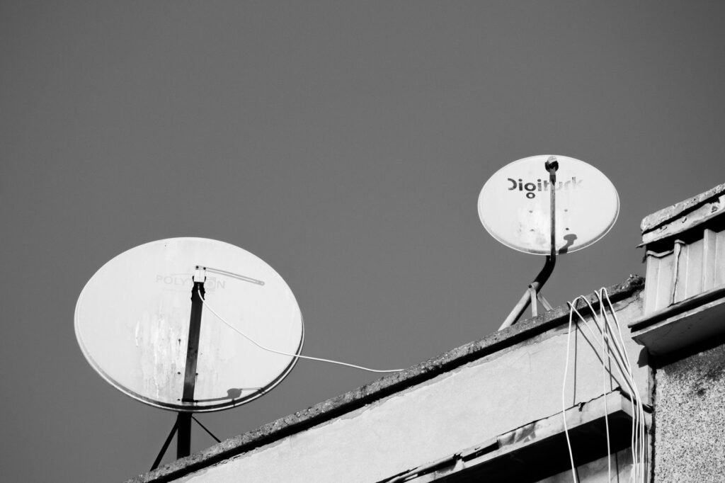 Monochrome image of two satellite dishes on a rooftop, representing communication technology.