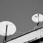 Monochrome image of two satellite dishes on a rooftop, representing communication technology.