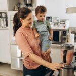 Mother and child using a blender together in a cozy kitchen setting.