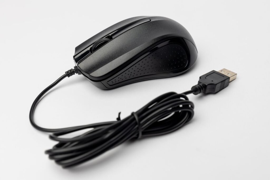 Close-up of a black wired computer mouse on a white background, showcasing its design and connection cable.