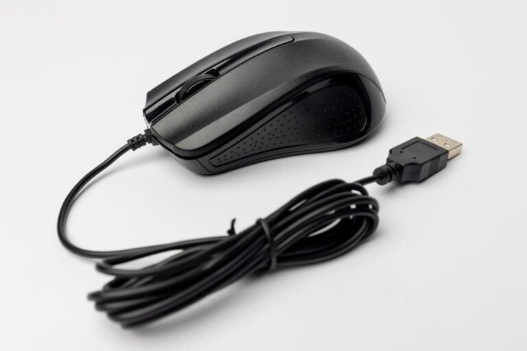 Close-up of a black wired computer mouse on a white background, showcasing its design and connection cable.