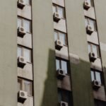 Facade of a city apartment building equipped with air conditioners on each window.