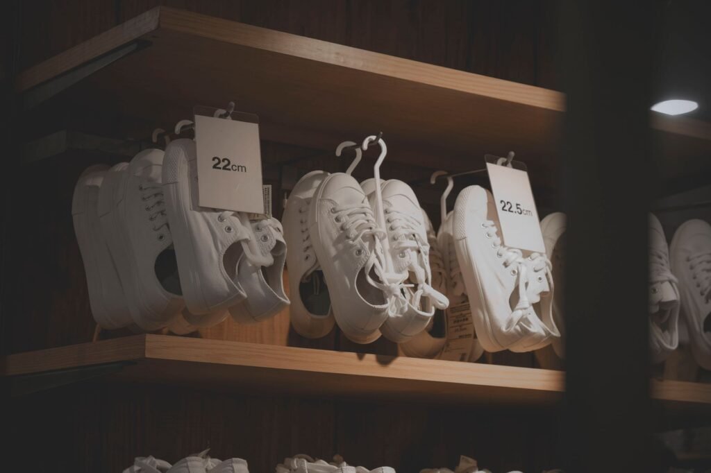 White sneakers elegantly displayed in a modern shop interior, showcasing minimalistic design on wooden shelves.