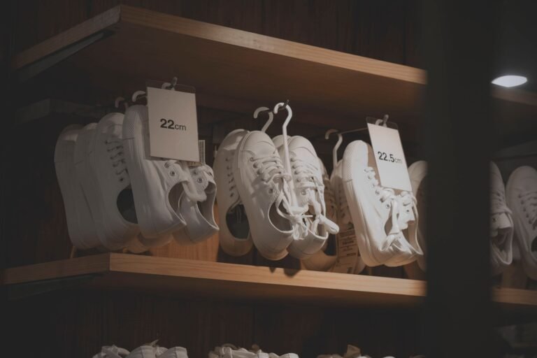 White sneakers elegantly displayed in a modern shop interior, showcasing minimalistic design on wooden shelves.