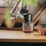 A cozy kitchen featuring a coffee maker and kitchen tools on a wooden counter, emphasizing a warm home vibe.