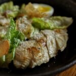 A flavorful Caesar salad topped with grilled chicken and hard-boiled eggs.