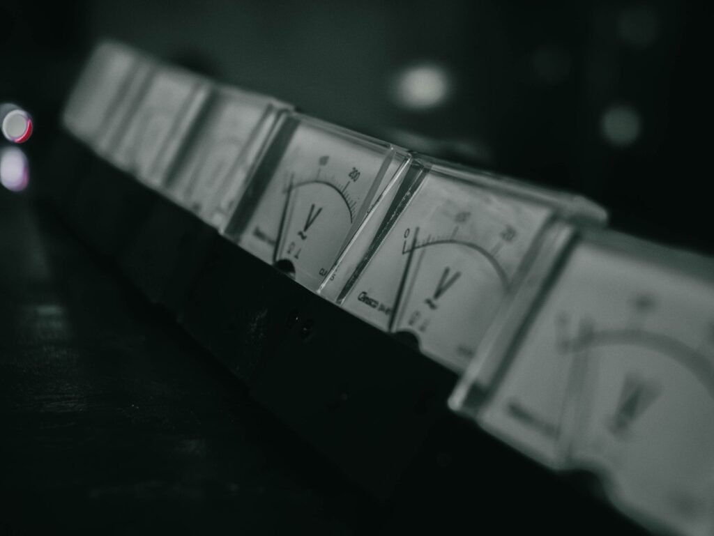 Close-up of vintage analog voltage meters in a dark industrial setting with a moody atmosphere.