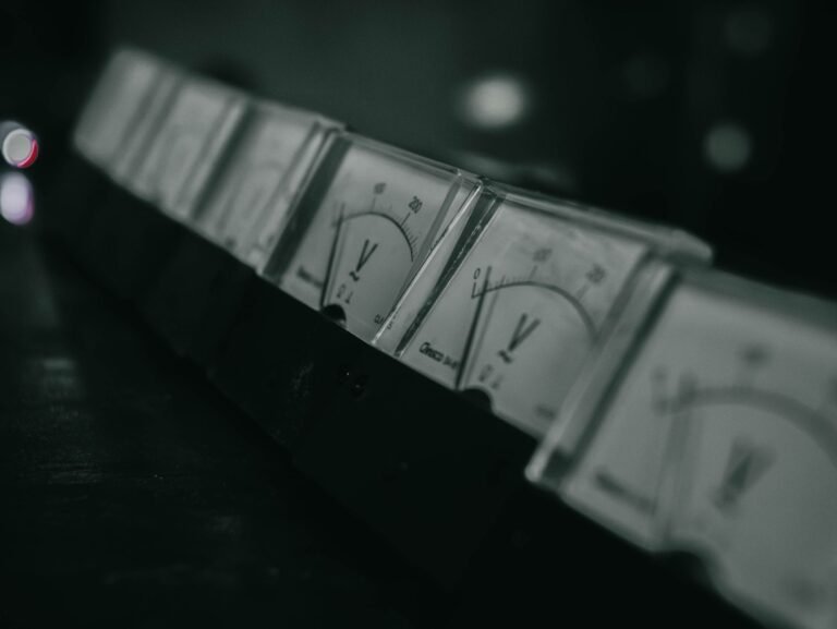 Close-up of vintage analog voltage meters in a dark industrial setting with a moody atmosphere.