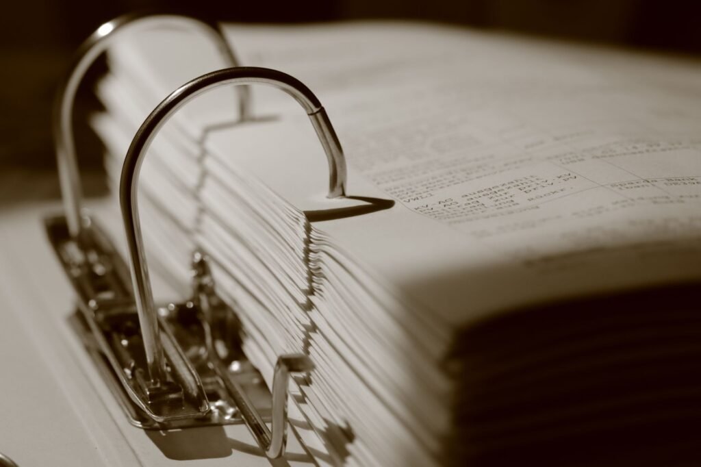 Detailed sepia close-up of a binder filled with documents, emphasizing texture.