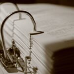 Detailed sepia close-up of a binder filled with documents, emphasizing texture.