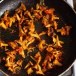 Delicious sautéed chanterelle mushrooms cooking in a frying pan, perfect for a gourmet meal.
