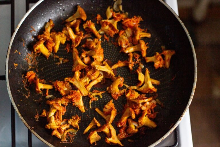Delicious sautéed chanterelle mushrooms cooking in a frying pan, perfect for a gourmet meal.