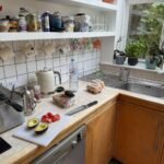 Kitchen counter with fresh avocado, tomatoes, and kitchenware near a bright window.