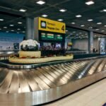 Modern baggage claim area at Suvarnabhumi Airport in Bangkok with luggage carousel and signage.