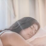 Portrait of a woman sleeping peacefully in soft morning light indoors.