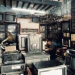 A cluttered vintage shop filled with antique radios, TVs, and a man working in the background.