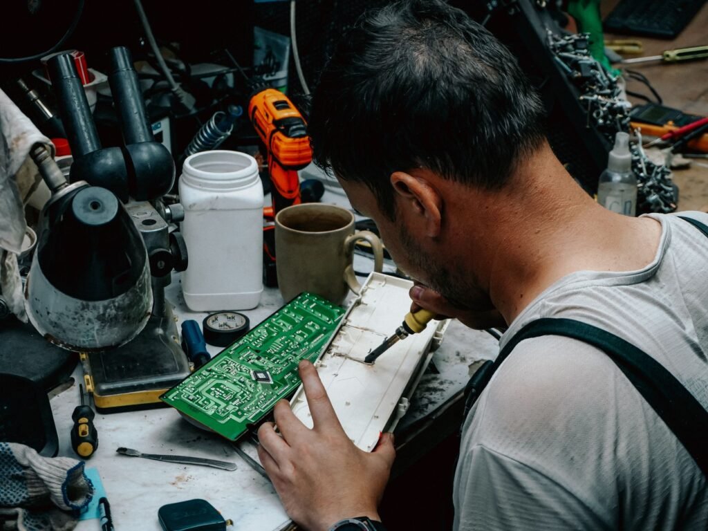 Close-up of a technician soldering a circuit board in a workshop, focusing on precise electronics work.