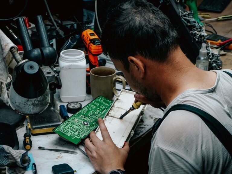 Close-up of a technician soldering a circuit board in a workshop, focusing on precise electronics work.
