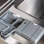 A detailed view of a dishwasher detergent compartment with soap residue.