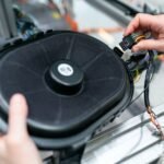 Close-up of an engineer working on a sound system speaker assembly in a workshop.