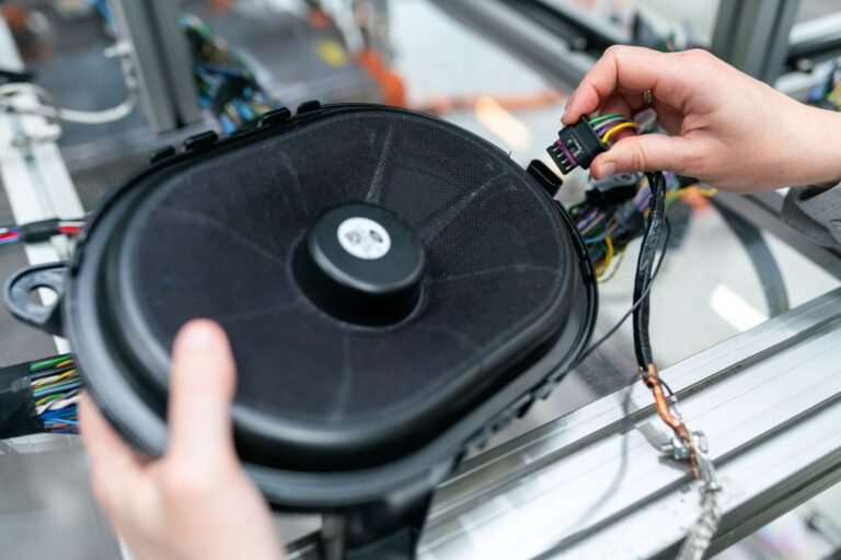 Close-up of an engineer working on a sound system speaker assembly in a workshop.