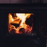 A close-up of a wood-burning fireplace emitting warmth with flickering flames and glowing embers.