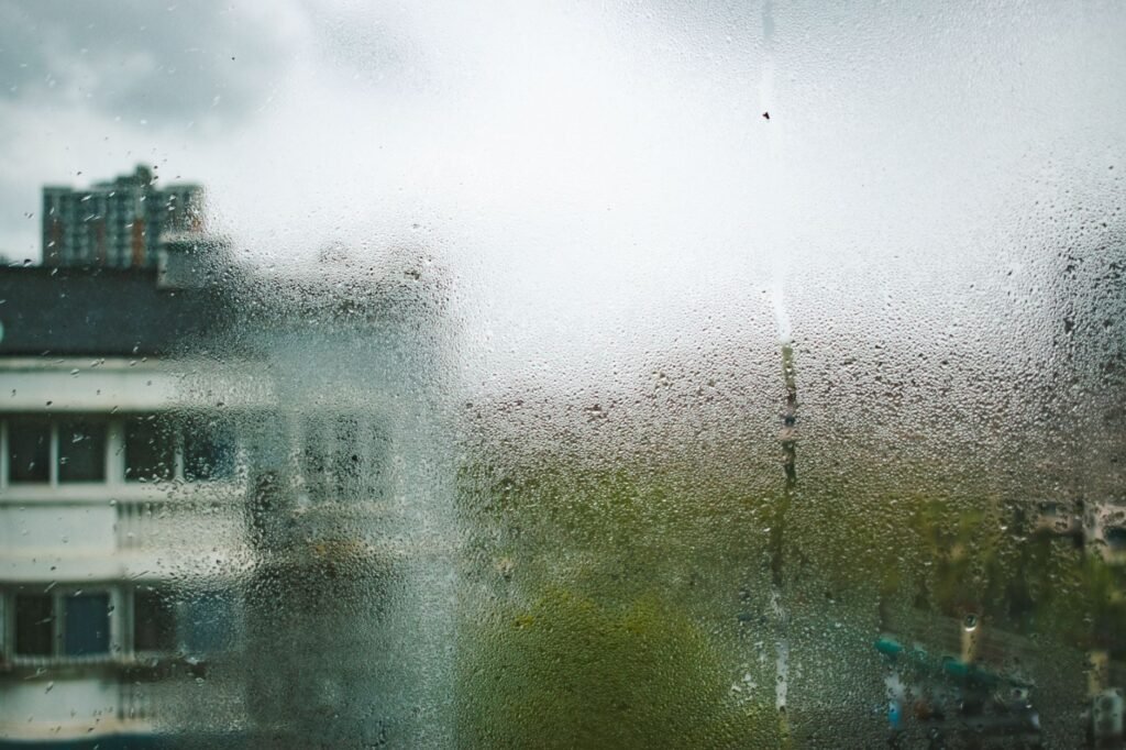 View of Shanghai buildings through a dewy, moisture-covered window during a cloudy day.