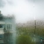 View of Shanghai buildings through a dewy, moisture-covered window during a cloudy day.