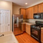 Contemporary kitchen featuring wooden cabinets, stainless steel refrigerator, and modern appliances.