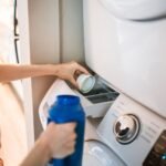 Close-up of a person pouring detergent into a front-loading washer, emphasizing household chores.