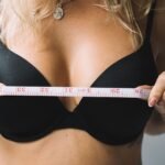 Close-up of a woman measuring her bust with tape for the perfect bra fit.