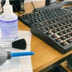 Set of tools and cleaning products for mechanical keyboard maintenance on a wooden desk.