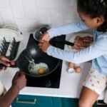 A child helps prepare breakfast, cracking eggs in a modern kitchen setting.