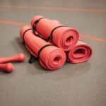 Red exercise mats and dumbbells on a gym floor, perfect for home or studio fitness.